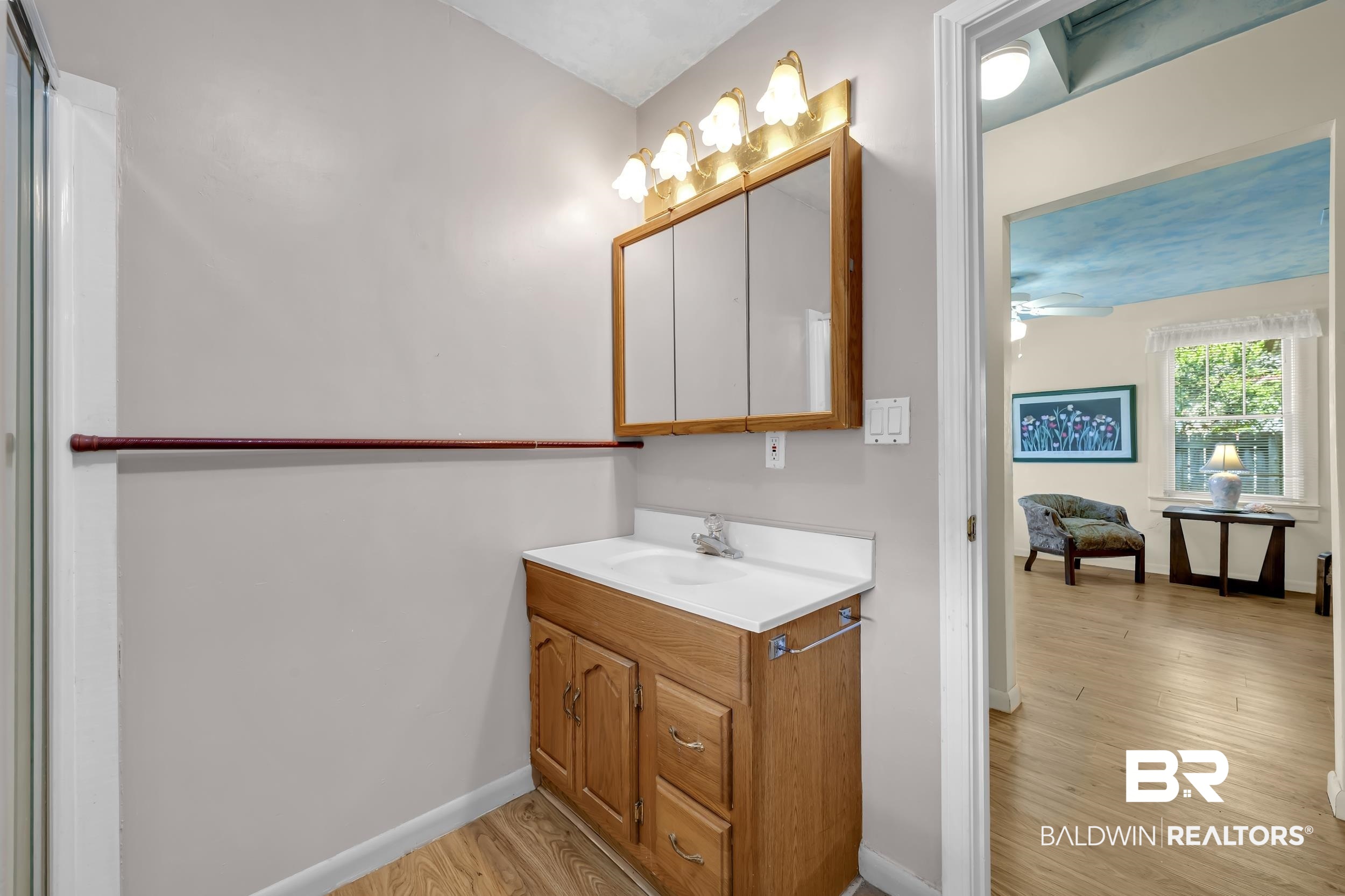 304 West Myrtle Avenue Foley, AL 36535 - Photo 14 of 29 Bathroom vanity featuring a wood-finish cabinet, white countertop with integrated sink, and an overhead medicine cabinet with mirror