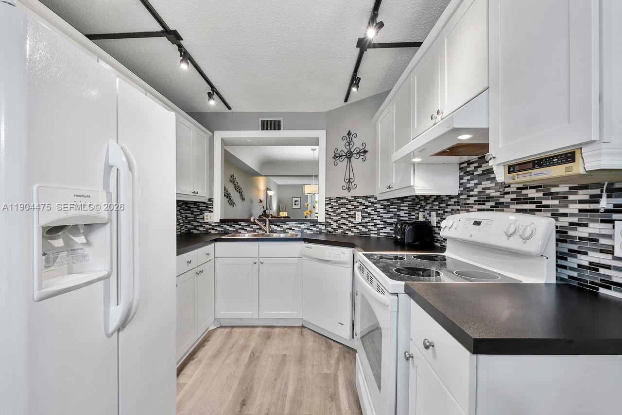 23249 Barwood Lane North, Unit 102 Boca Raton, FL 33428 - Photo 23 of 45 a kitchen with stainless steel appliances granite countertop a sink a stove and a refrigerator