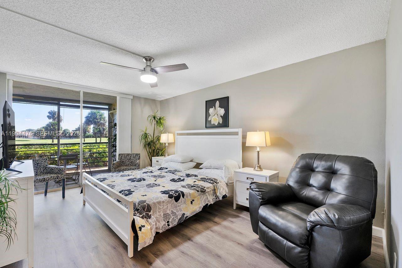 23249 Barwood Lane North, Unit 102 Boca Raton, FL 33428 - Photo 29 of 45 a bedroom with a bed couch and a large window