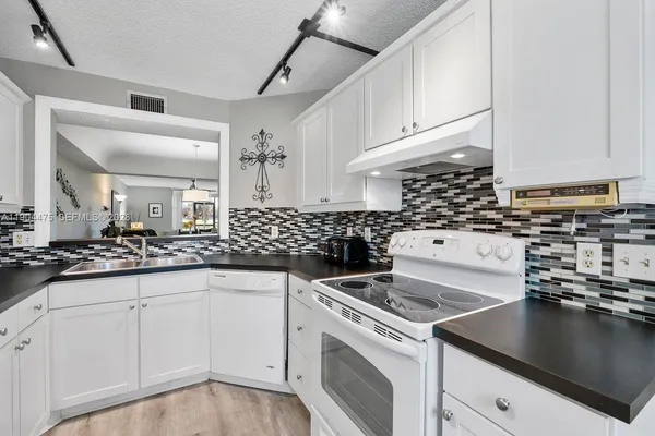 a kitchen with granite countertop a sink a stove and cabinets