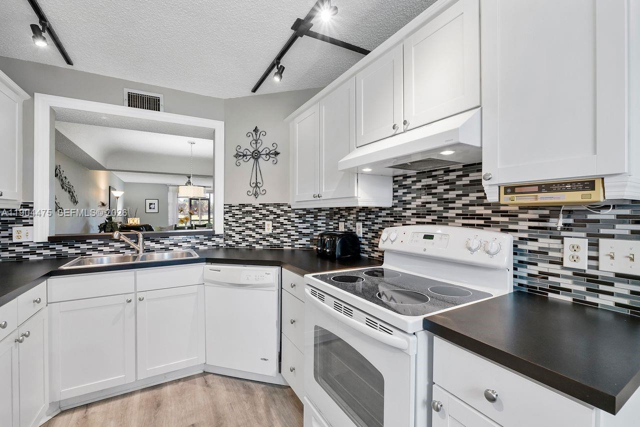 23249 Barwood Lane North, Unit 102 Boca Raton, FL 33428 - Photo 31 of 45 a kitchen with granite countertop a sink a stove and cabinets