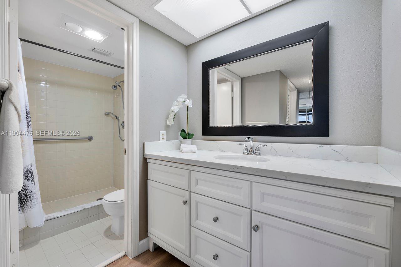 23249 Barwood Lane North, Unit 102 Boca Raton, FL 33428 - Photo 7 of 45 a bathroom with a toilet sink and mirror