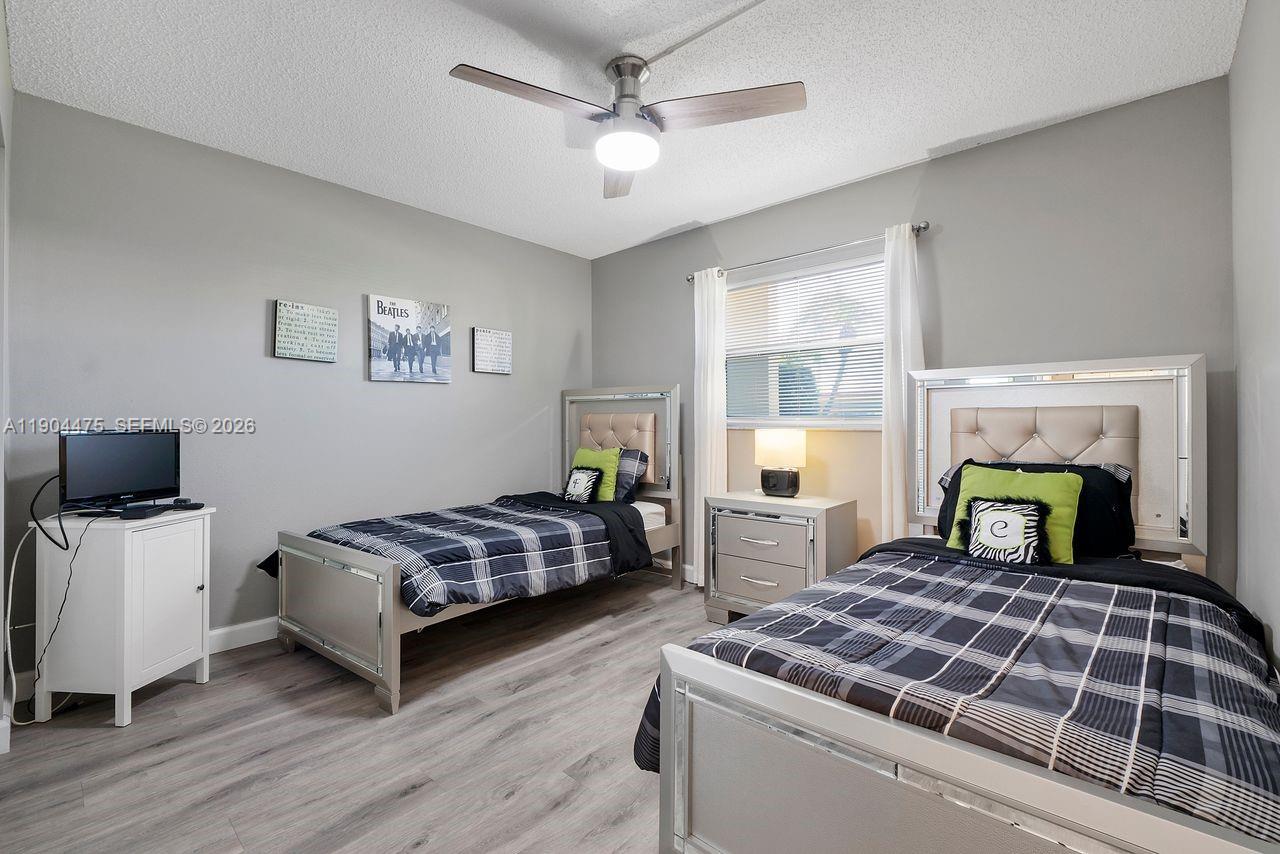 23249 Barwood Lane North, Unit 102 Boca Raton, FL 33428 - Photo 9 of 45 a bedroom with a bed and wooden floor
