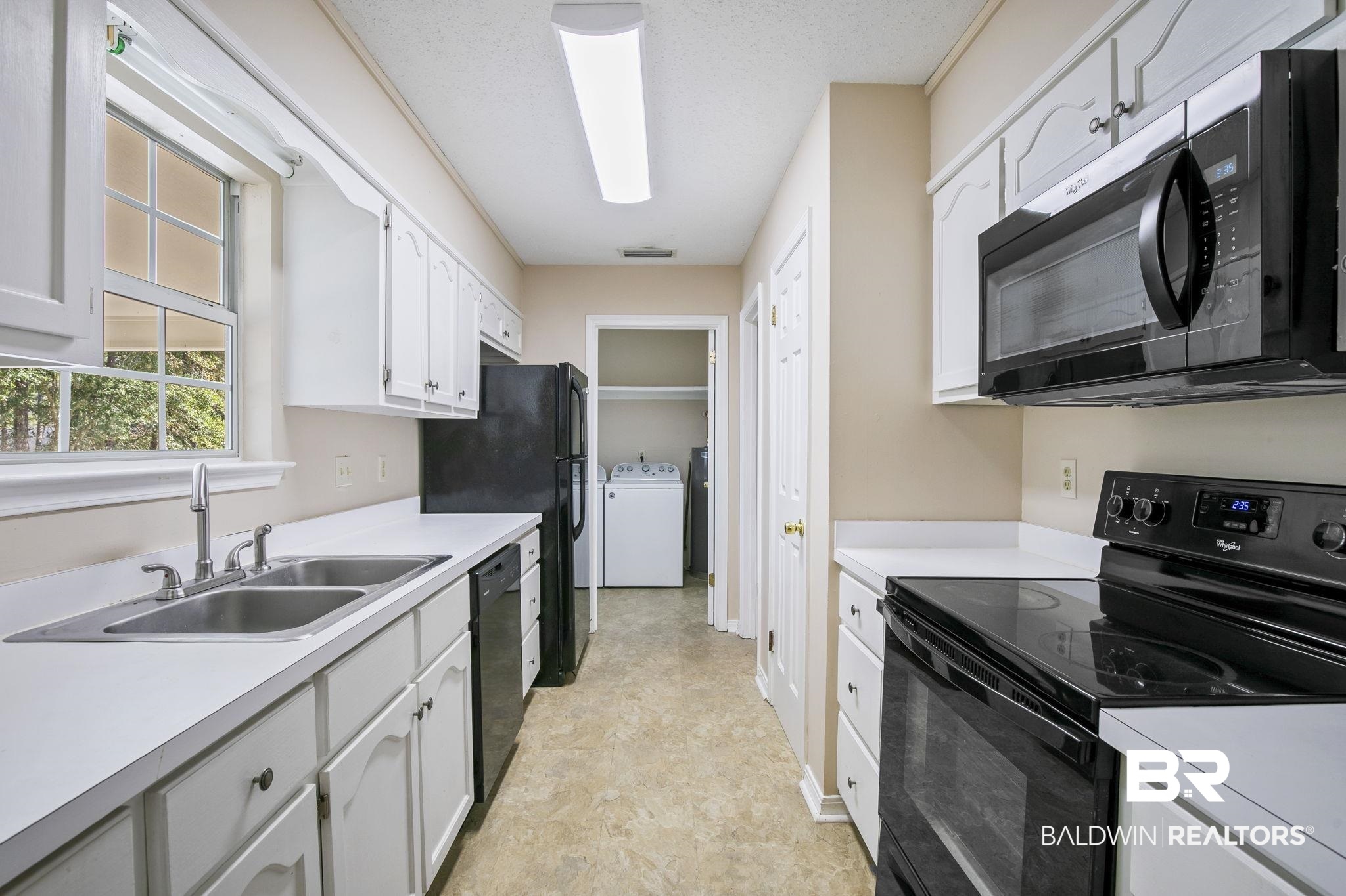 359 Ridgewood Drive Daphne, AL 36526 - Photo 19 of 73 Kitchen with washer / dryer, white cabinets, a textured ceiling, black appliances, and sink