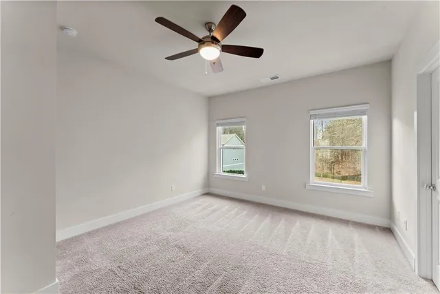 an empty room with ceiling fan and windows
