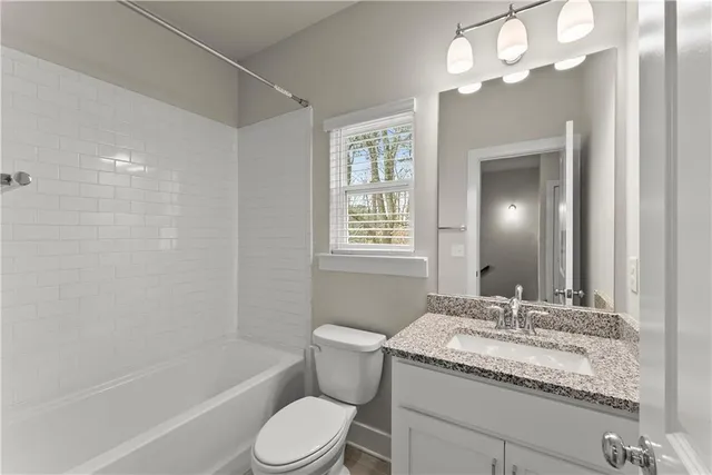 a bathroom with a granite countertop sink a toilet and bathtub