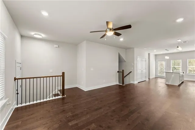 a view of an empty room with wooden floor and a ceiling fan
