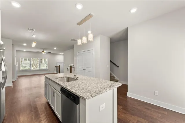 a kitchen with granite countertop kitchen island a sink appliances and wooden floor