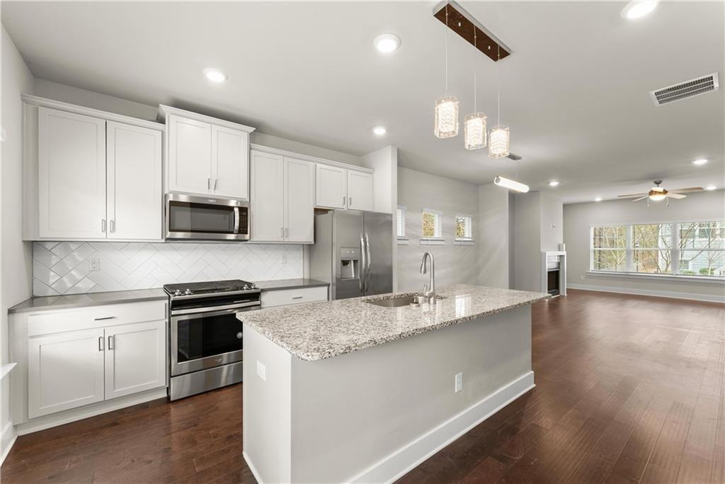 2178 Wiggins Walk Atlanta, GA 30316 - Photo 10 of 31 a large kitchen with stainless steel appliances kitchen island granite countertop a stove a sink dishwasher and a refrigerator with wooden floor