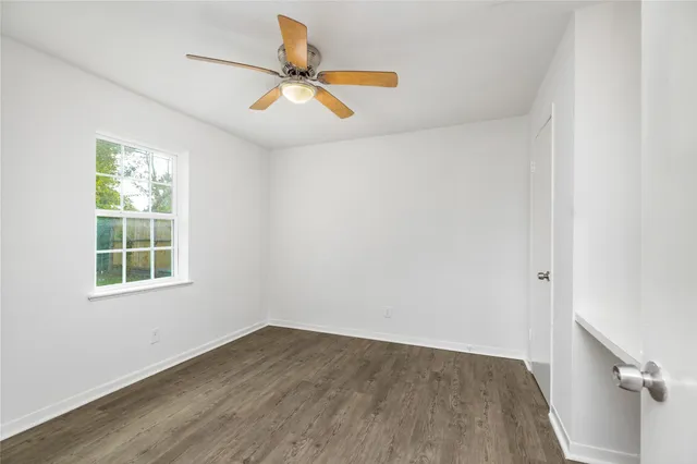 an empty room with wooden floor fan and windows