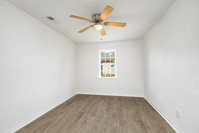 an empty room with a window and a ceiling fan