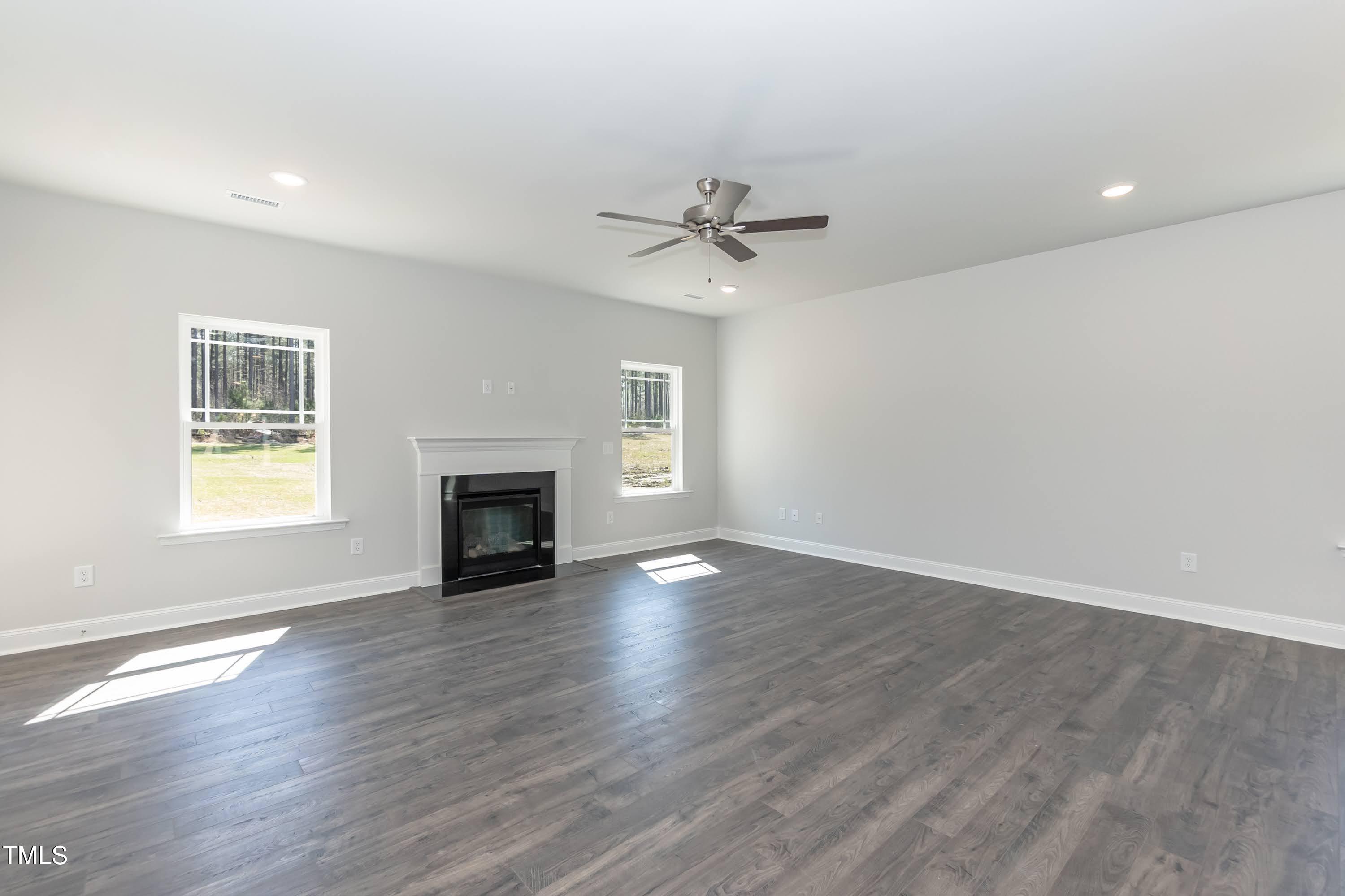 45 High Hampton Way Fuquay-Varina, NC 27526 - Photo 12 of 43 an empty room with windows a fireplace and a ceiling fan