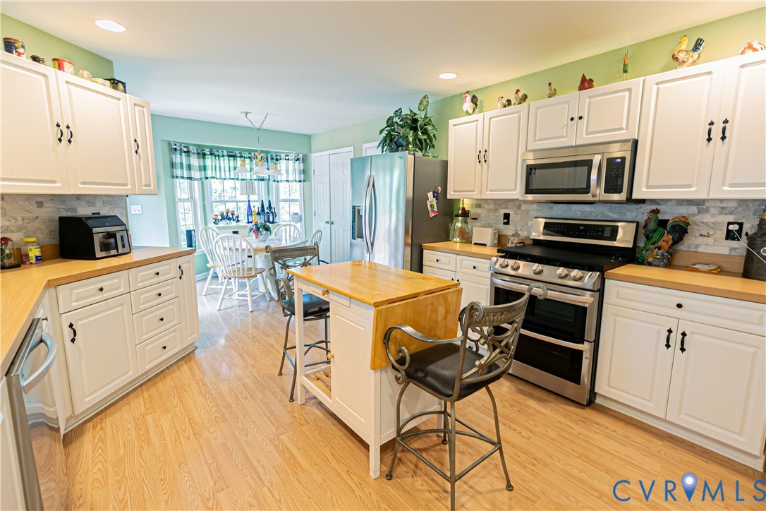401 Loyalist Drive Ruther Glen, VA 22546 - Photo 14 of 44 a kitchen with stainless steel appliances a stove a sink dishwasher a refrigerator white cabinets with wooden floor