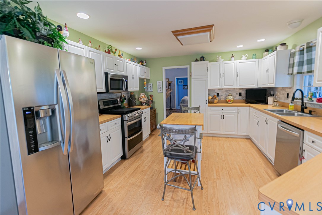 401 Loyalist Drive Ruther Glen, VA 22546 - Photo 16 of 44 a kitchen with stainless steel appliances a stove a sink a refrigerator white cabinets and wooden floor