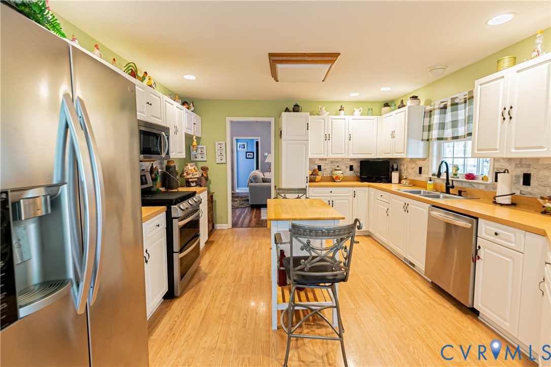 401 Loyalist Drive Ruther Glen, VA 22546 - Photo 17 of 45 a kitchen with stainless steel appliances a refrigerator a stove a sink dishwasher and white cabinets with wooden floor