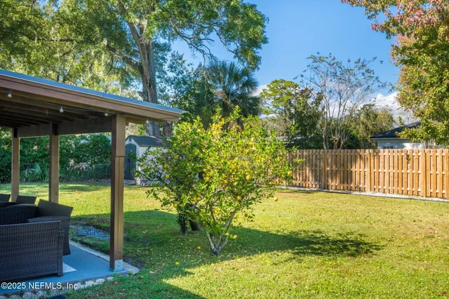 a view of a patio with couches potted plants and a big yard