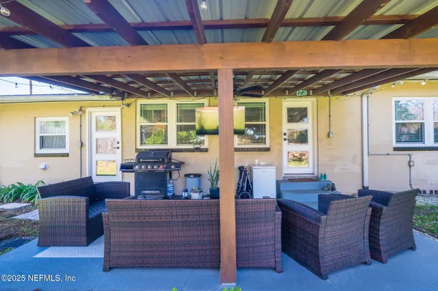a living room with patio furniture and a floor to ceiling window next to a yard