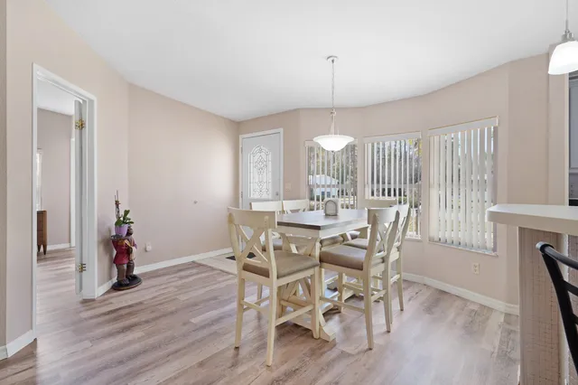 a kitchen with stainless steel appliances a dining table chairs refrigerator and cabinets