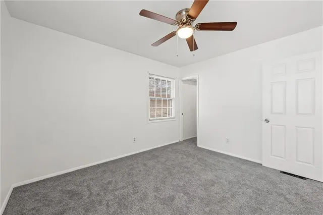 an empty room with ceiling fan and windows