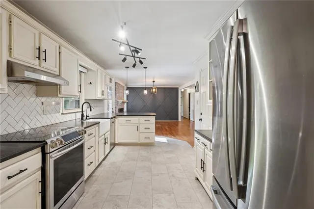 a large kitchen with stainless steel appliances a refrigerator sink and white cabinets