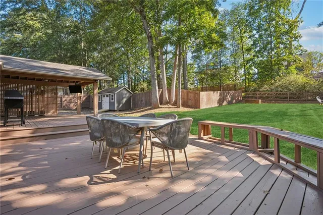 a view of a patio with table and chairs with wooden floor and fence