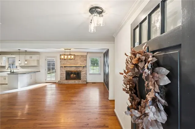 a view of a livingroom with a fireplace wooden floor and a kitchen