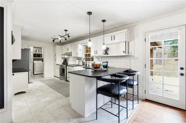 a kitchen with stainless steel appliances kitchen island granite countertop a stove a sink and a refrigerator with wooden floor