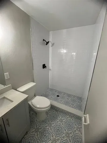 a white toilet sitting next to a bathroom sink and a shower