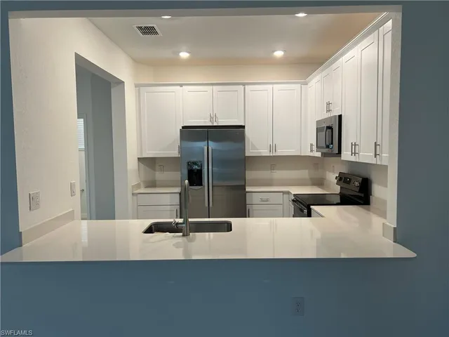 a kitchen with granite countertop a refrigerator sink and cabinets
