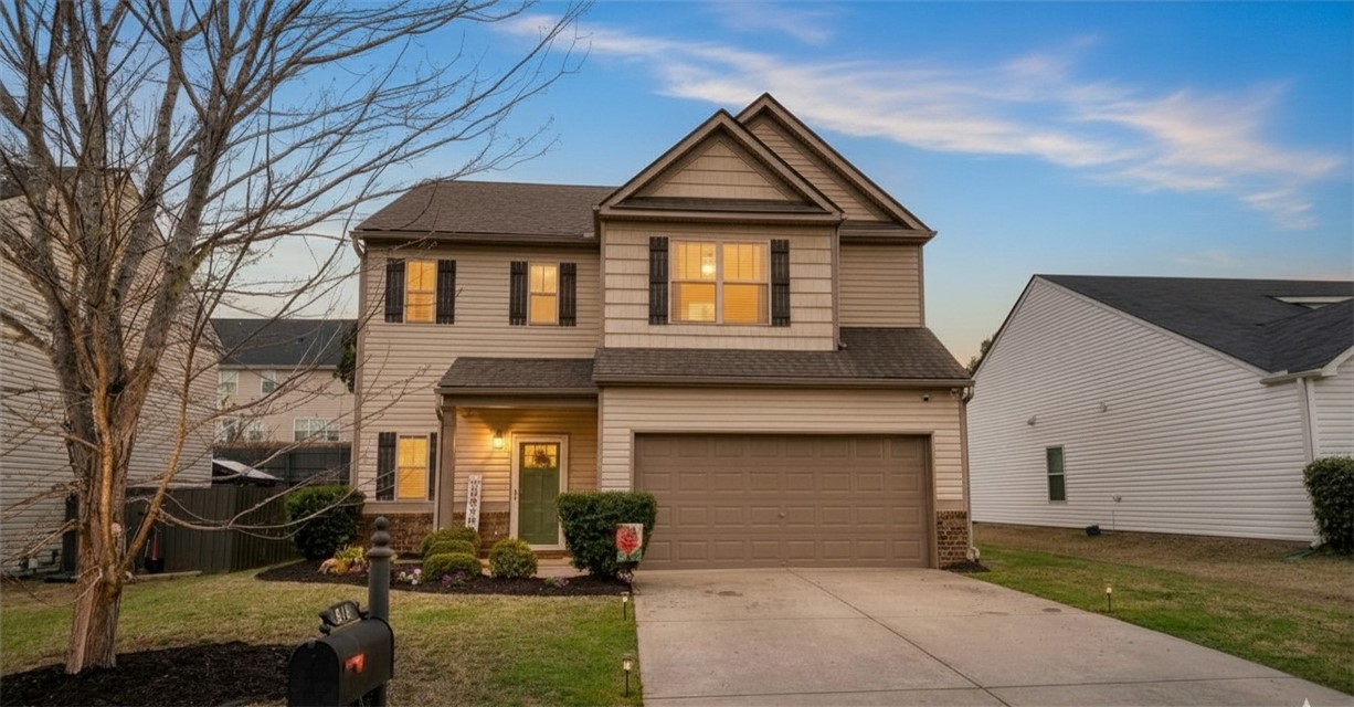 This inviting residence features classic siding, an attached garage, and a well-maintained front yard.