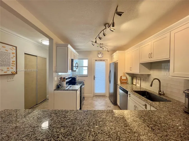 a kitchen with stainless steel appliances granite countertop a sink a stove and refrigerator