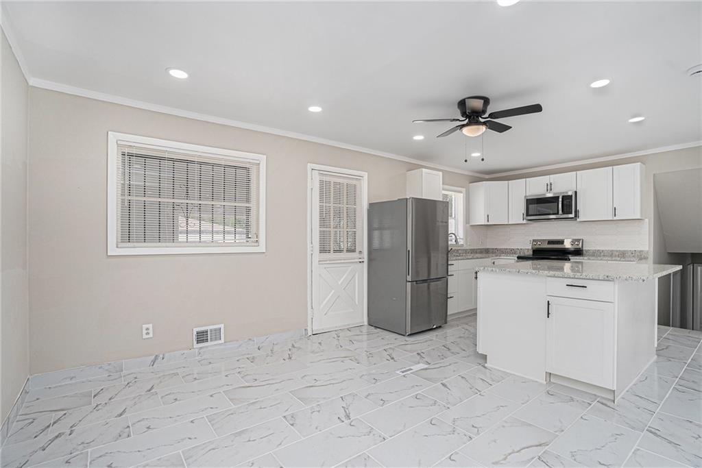 2403 Tiffany Place Decatur, GA 30035 - Photo 12 of 29 a kitchen with stainless steel appliances kitchen island granite countertop a refrigerator a stove a sink dishwasher a refrigerator with white cabinets and wooden floor
