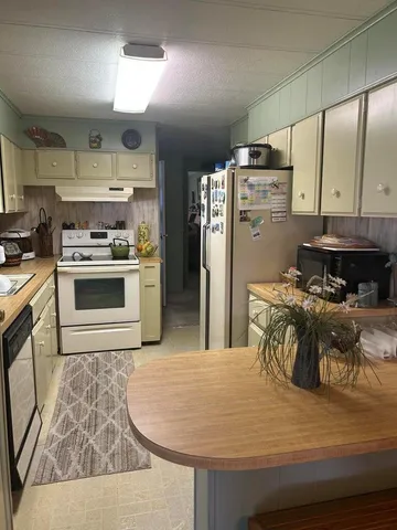 a kitchen with stainless steel appliances granite countertop a refrigerator a stove and a sink with wooden floors