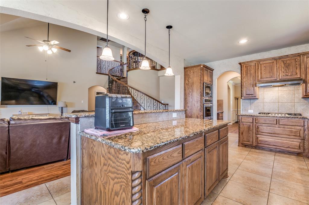 1512 Ruffian Road DeSoto, TX 75115 - Photo 8 of 25 a kitchen with stainless steel appliances kitchen island granite countertop a stove a sink and a refrigerator
