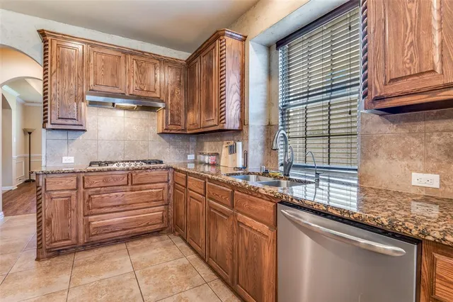 a kitchen with kitchen island granite countertop wooden cabinets a sink and dishwasher