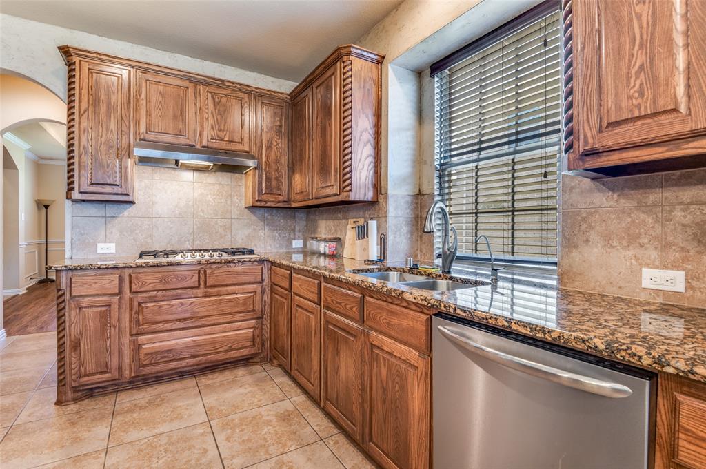 1512 Ruffian Road DeSoto, TX 75115 - Photo 9 of 25 a kitchen with kitchen island granite countertop wooden cabinets a sink and dishwasher