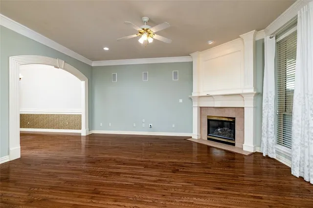 a view of an empty room with wooden floor fireplace and a window