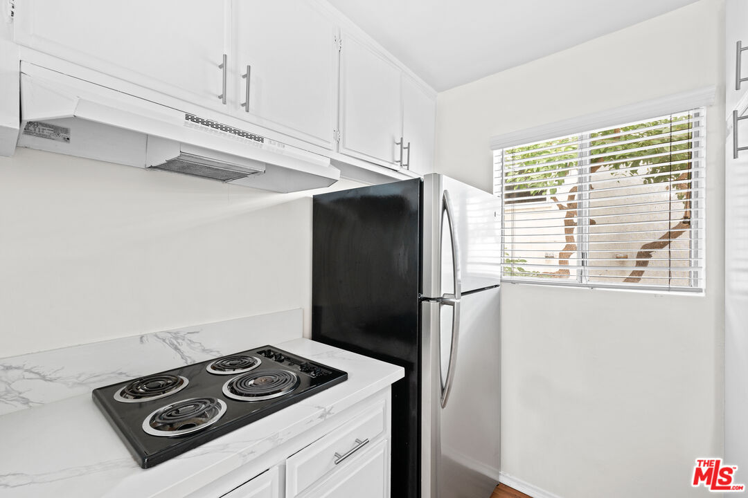 1206 South Holt Avenue, Unit 2 Los Angeles, CA 90035 - Photo 7 of 17 a kitchen with stainless steel appliances a refrigerator a stove and white cabinets