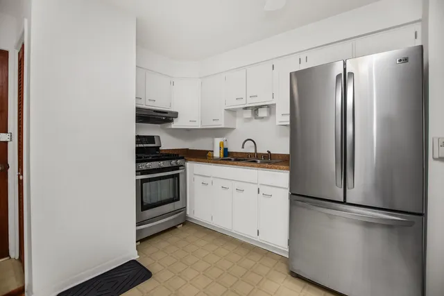 a kitchen with stainless steel appliances a refrigerator a stove and white cabinets