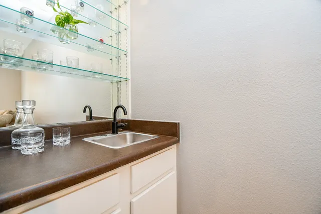a sink with a granite countertop lots of white and green space