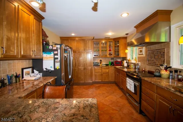 a kitchen with stainless steel appliances granite countertop a sink refrigerator and cabinets