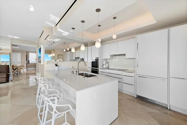 a kitchen with stainless steel appliances kitchen island granite countertop a stove a sink a refrigerator and white cabinets with wooden floor