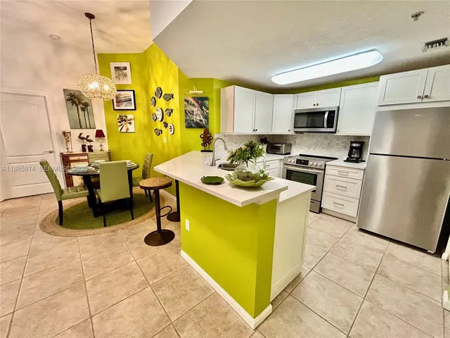 a kitchen with a refrigerator a stove top oven a dining table and chairs