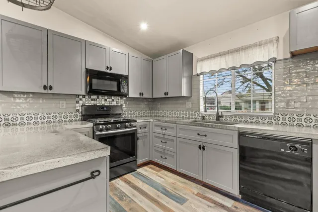 a kitchen with stainless steel appliances granite countertop a stove a sink and a microwave