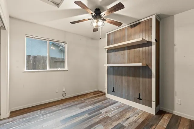 an empty room with a window and a chandelier fan