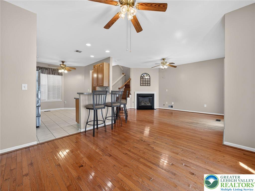 4312 Creek Road Allentown, PA 18104 - Photo 18 of 67 a view of a room with wooden floor a ceiling fan a fireplace and windows