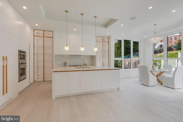 a large white kitchen with a large window and stainless steel appliances