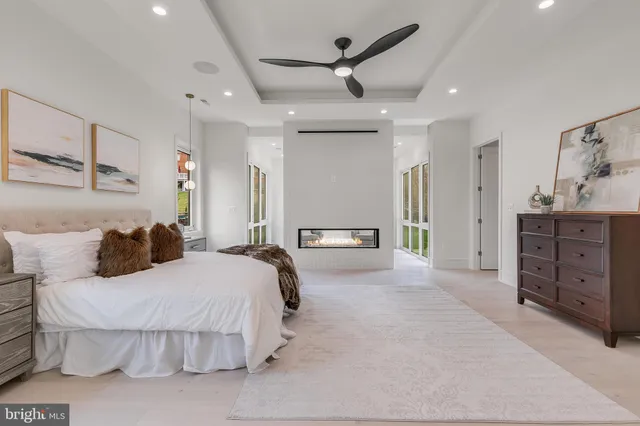 a spacious bedroom with a large bed a chandelier and a dresser