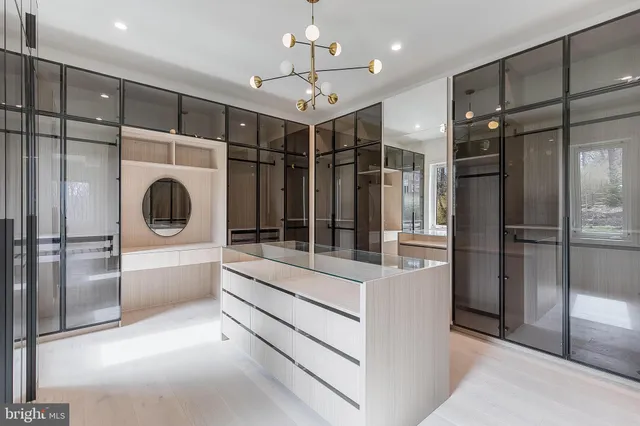 a large white kitchen with a large window a refrigerator and ceiling cabinets