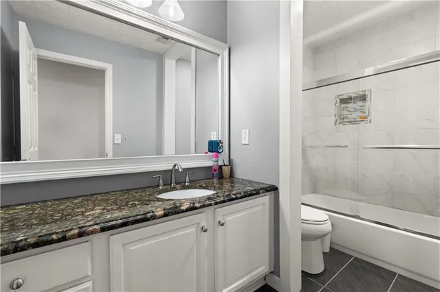 a bathroom with a granite countertop sink toilet and shower